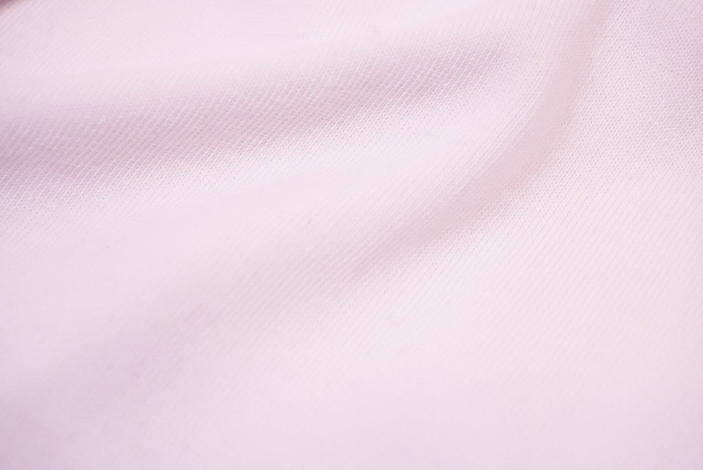 A close-up of white fabric with a fine woven texture and soft folds.