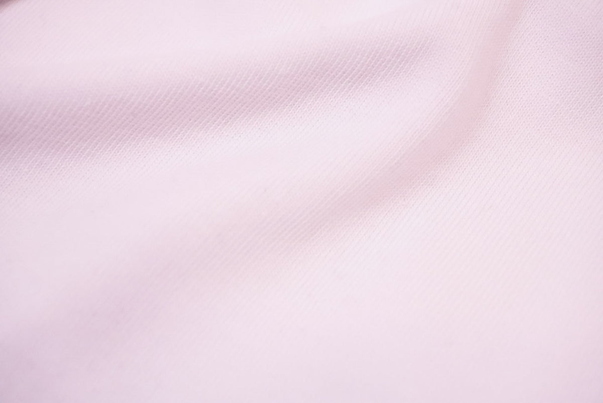 A close-up of white fabric with a fine woven texture and soft folds.