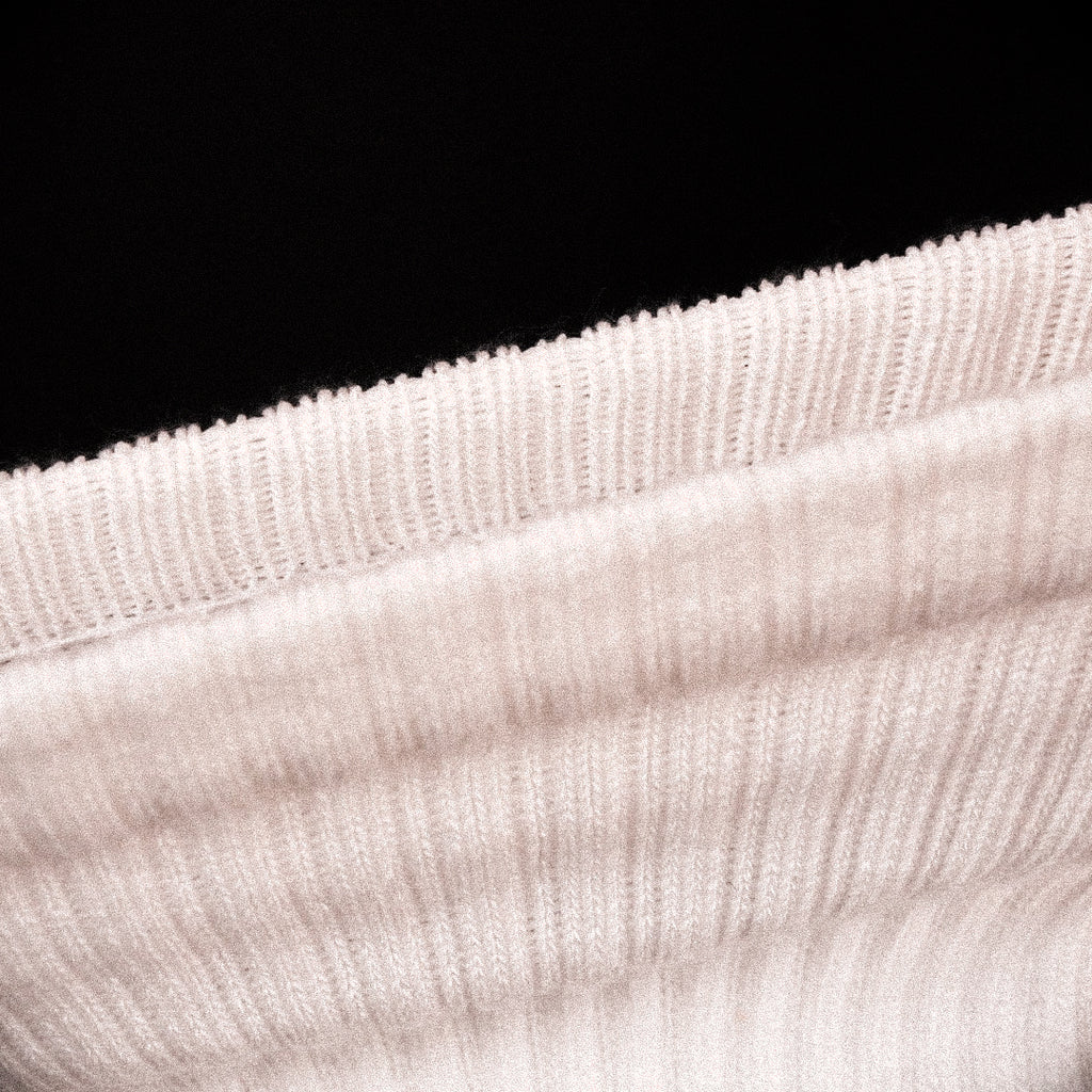 Close-up of a stretched ribbed knit fabric, shown against a solid black background.