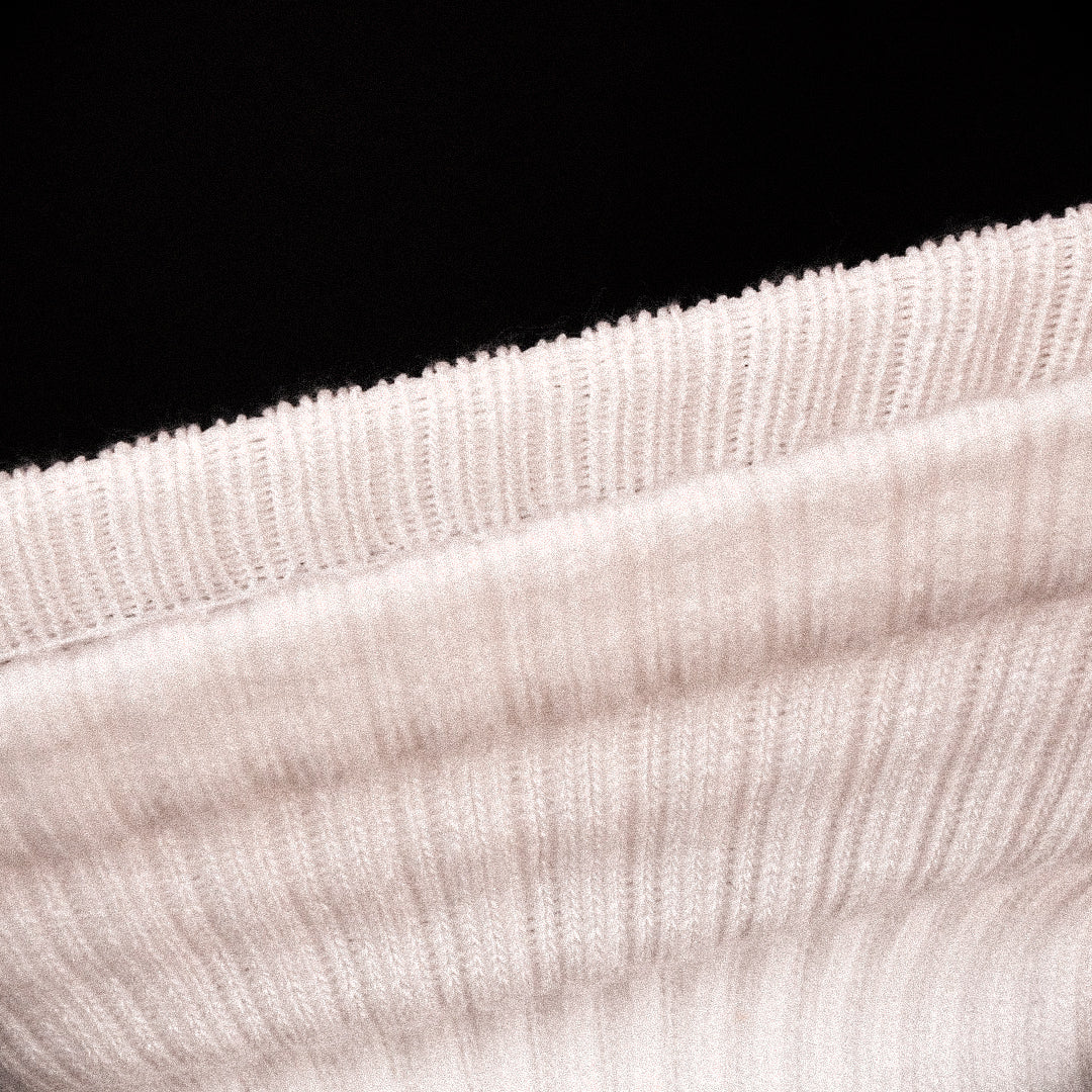 Close-up of a stretched ribbed knit fabric, shown against a solid black background.