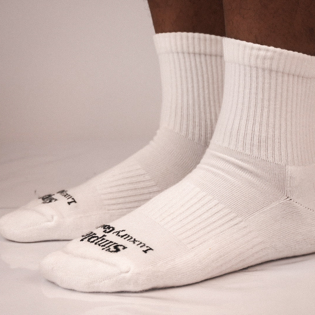 A pair of white ribbed quarter socks worn on feet, with black jacquard knitted branding text visible on the toes.